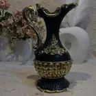 مزهرية ديكورية أنيقة باللون الأسود مع زخارف ذهبية بارزة