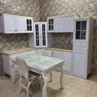 دولاب مطبخ أبيض مع طاولة طعام